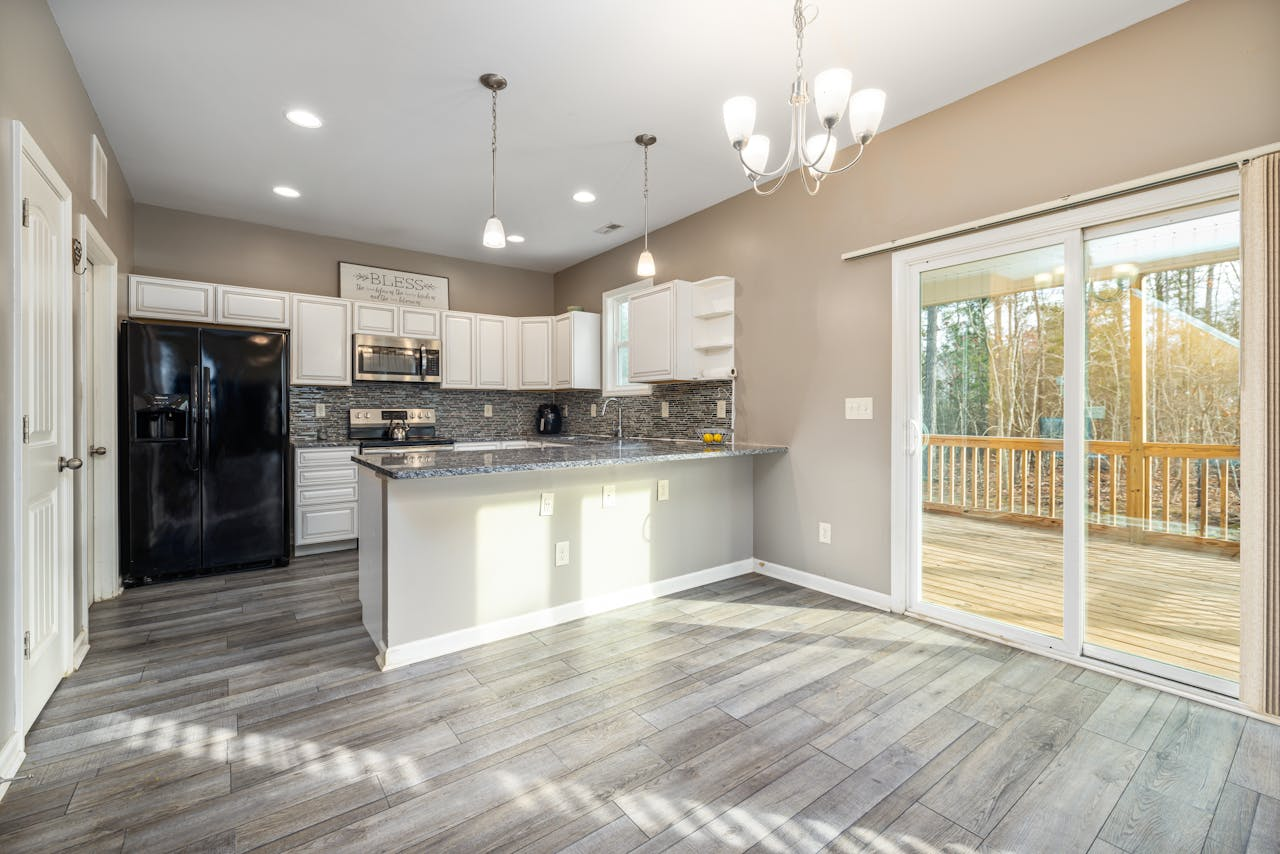 Contact Spacious modern kitchen with island and sliding doors to a balcony, ideal for culinary enthusiasts.