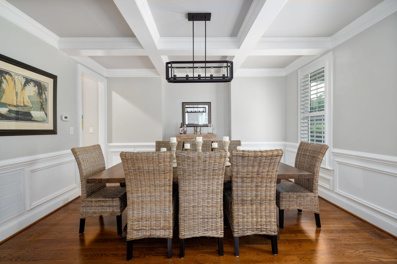 Services A beautifully designed dining room featuring wicker chairs, a wooden table, and minimalist decor.