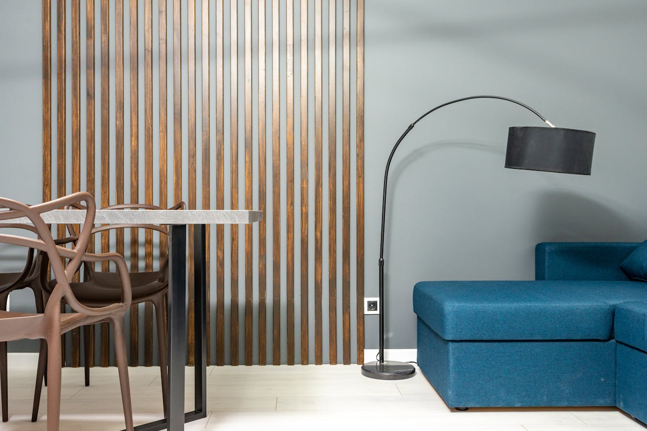 Contemporary living room interior with couch against lamp and table with armchairs on wooden floor at home